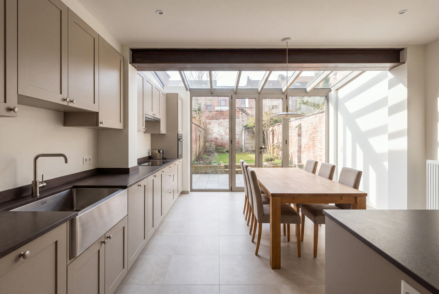 Cuisine rénovée d'une maison d'Anderlecht ouverte sur une annexe vitrée et le jardin