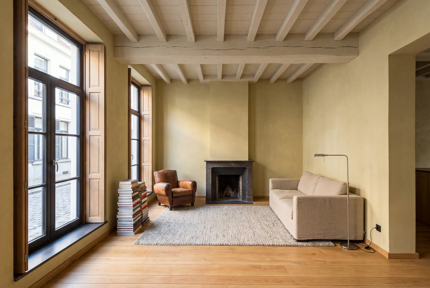 Séjour rénové d'une maison du Pentagone bruxellois avec poutres apparentes et volets intérieurs