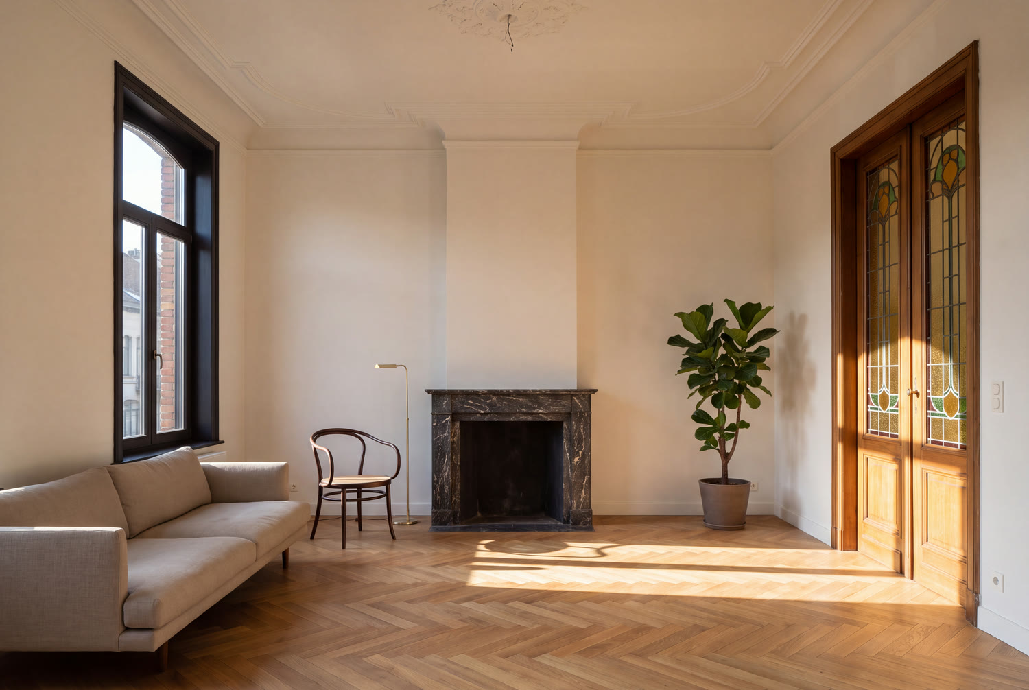 Séjour restauré d'une maison de Saint-Gilles avec corniche Art nouveau, cheminée en marbre et porte à vitrail