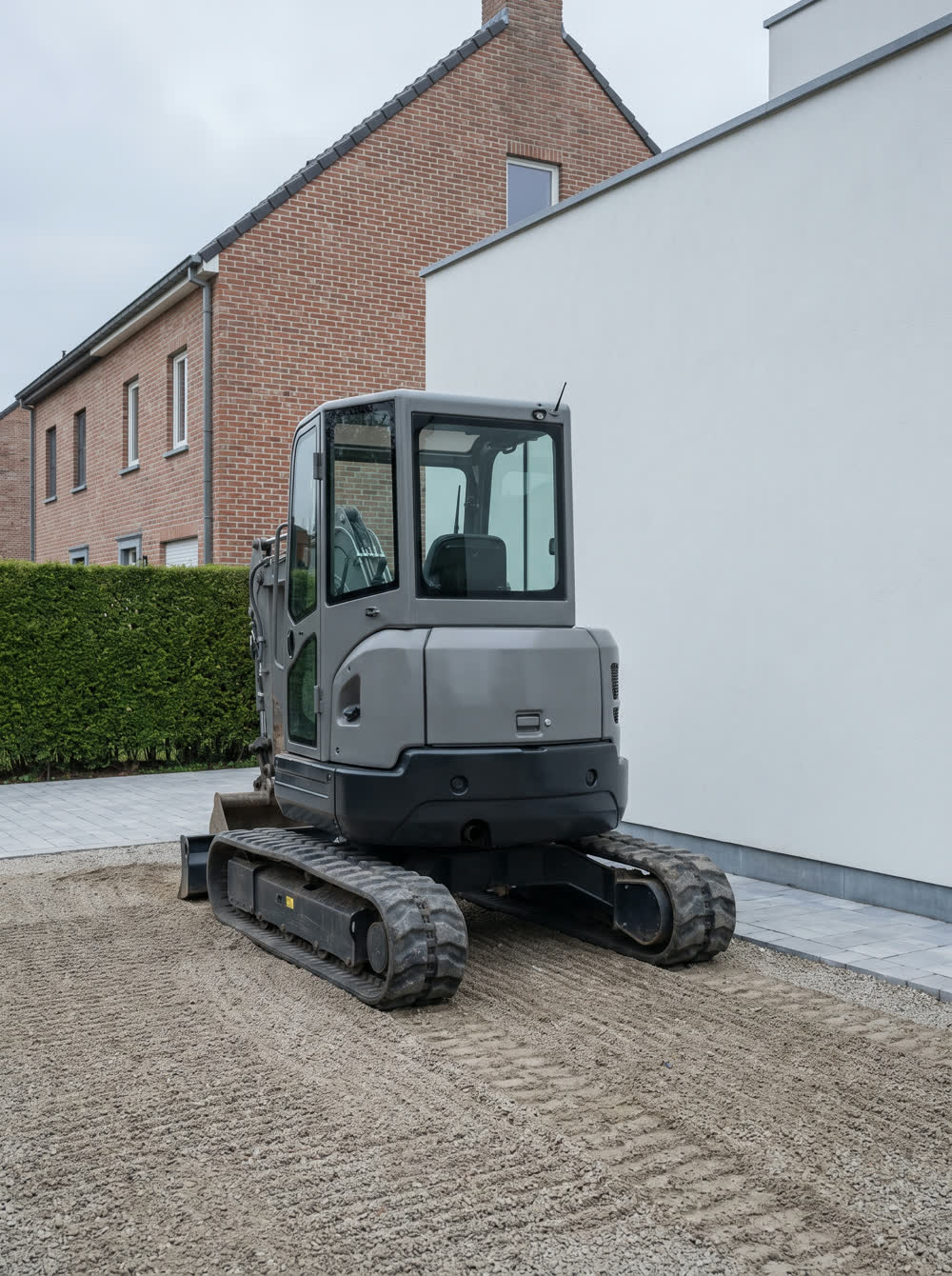 Mini-pelle compacte 2,5 tonnes stationnée devant une maison