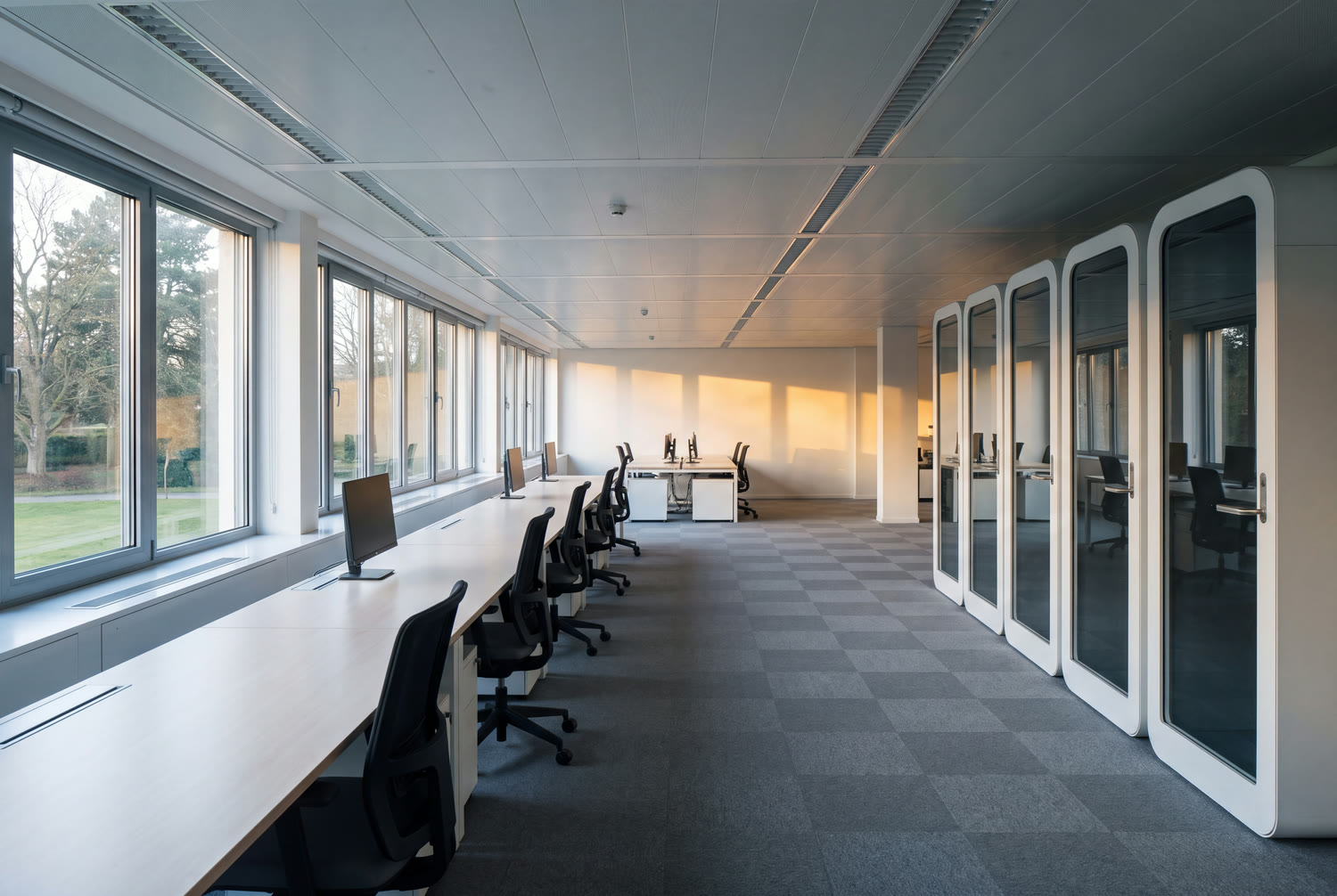 Large spotless office floor at daybreak in Woluwe, carpet vacuumed and desks cleared