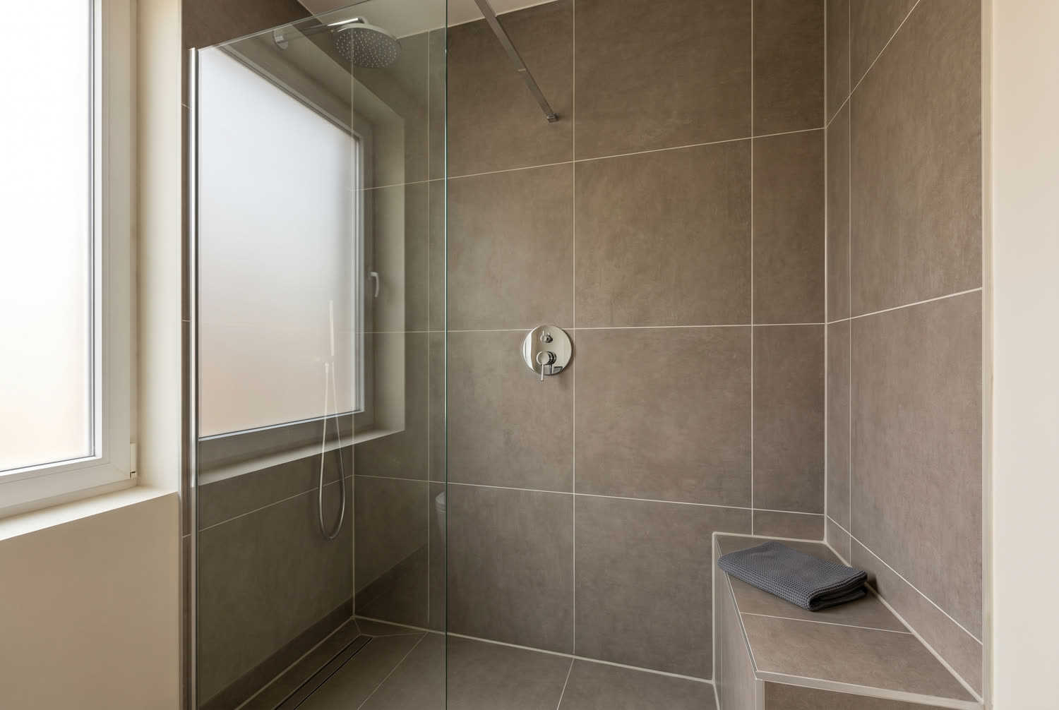 Douche à l'italienne carrelée en fin de chantier, paroi de verre et joints sans trace de silicone