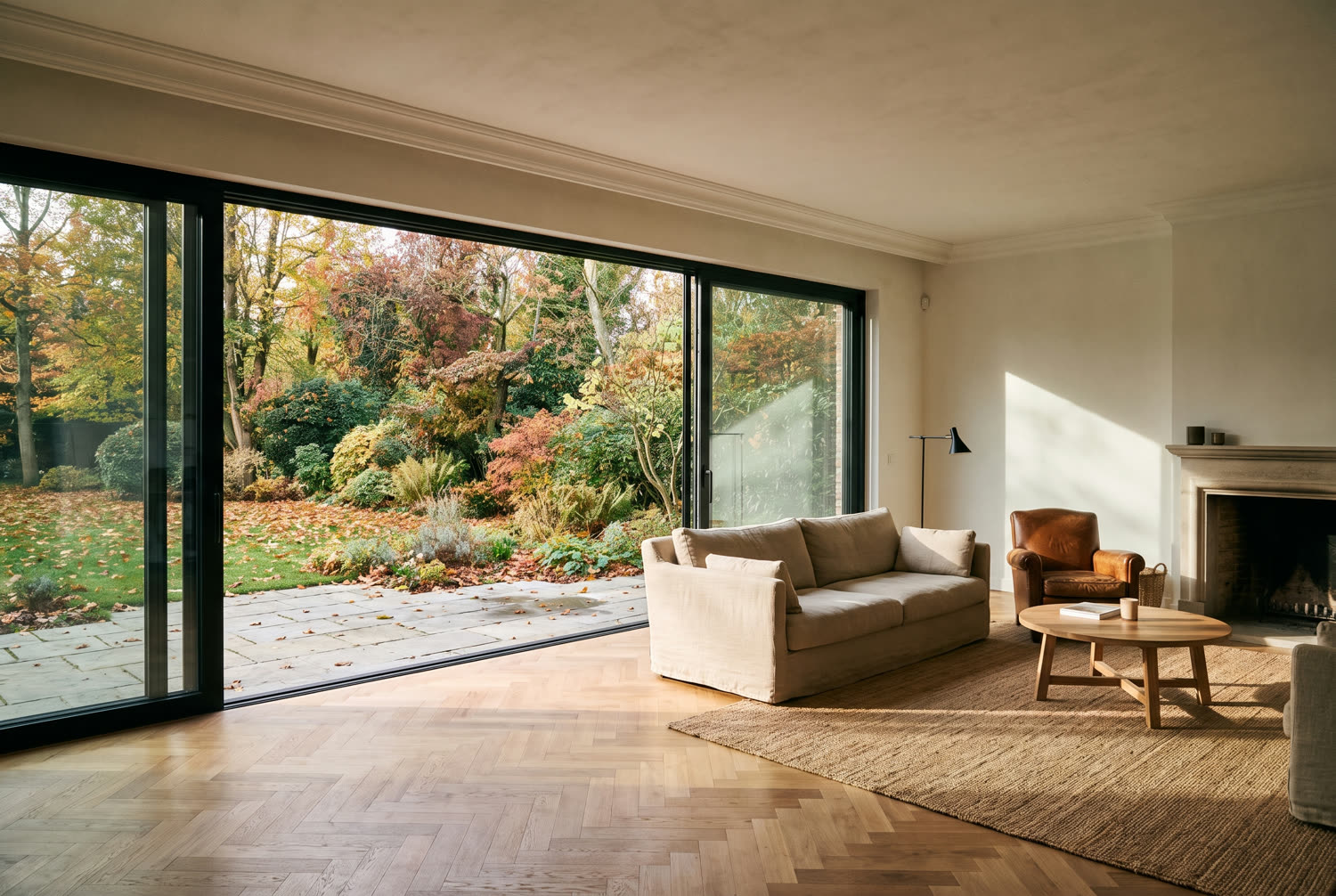 Séjour rénové d'une villa du Brabant wallon avec baie coulissante sur le jardin et parquet restauré