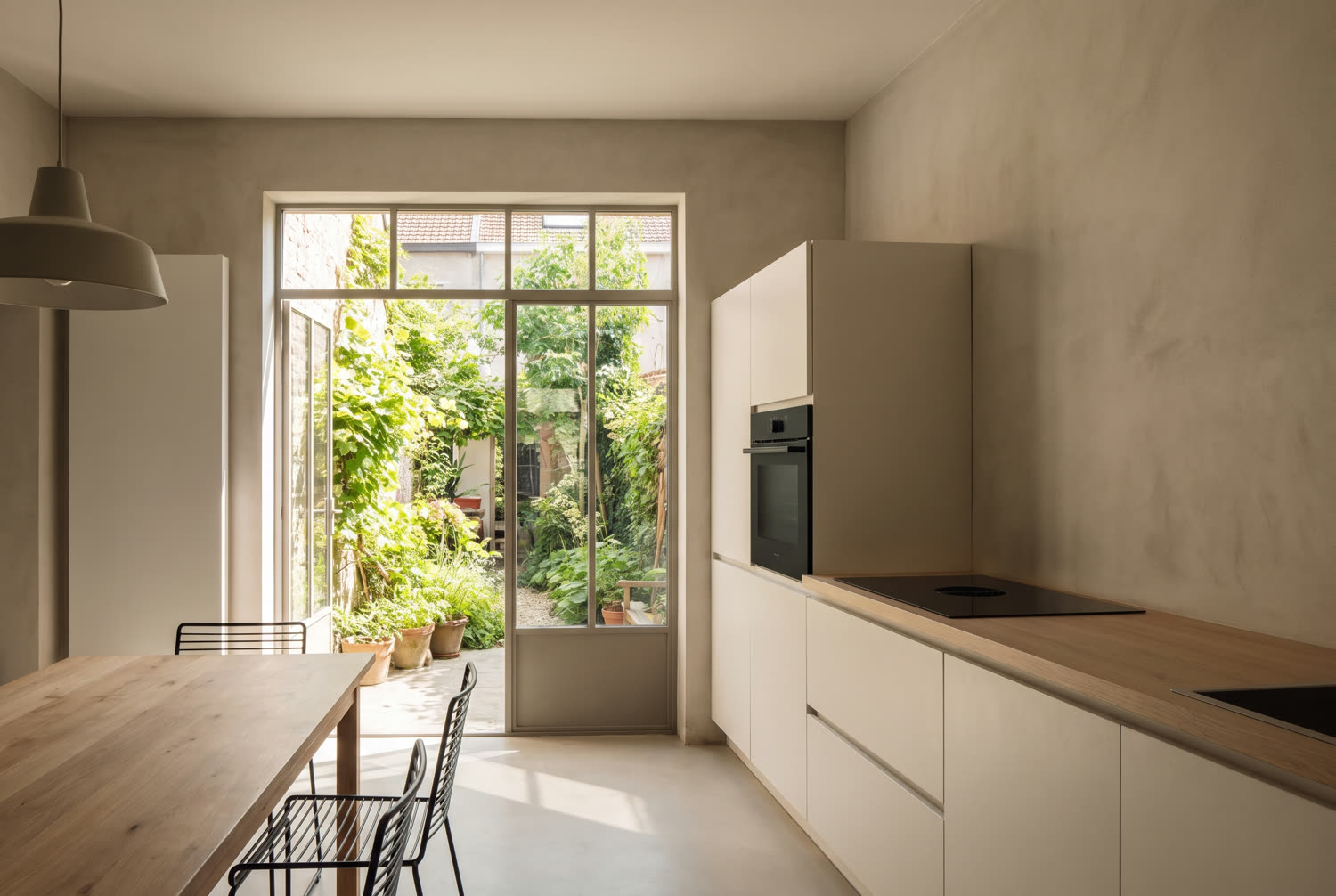 Cuisine rénovée d'une maison de Wavre, façades mates, plan de travail en bois et porte vitrée sur le jardin