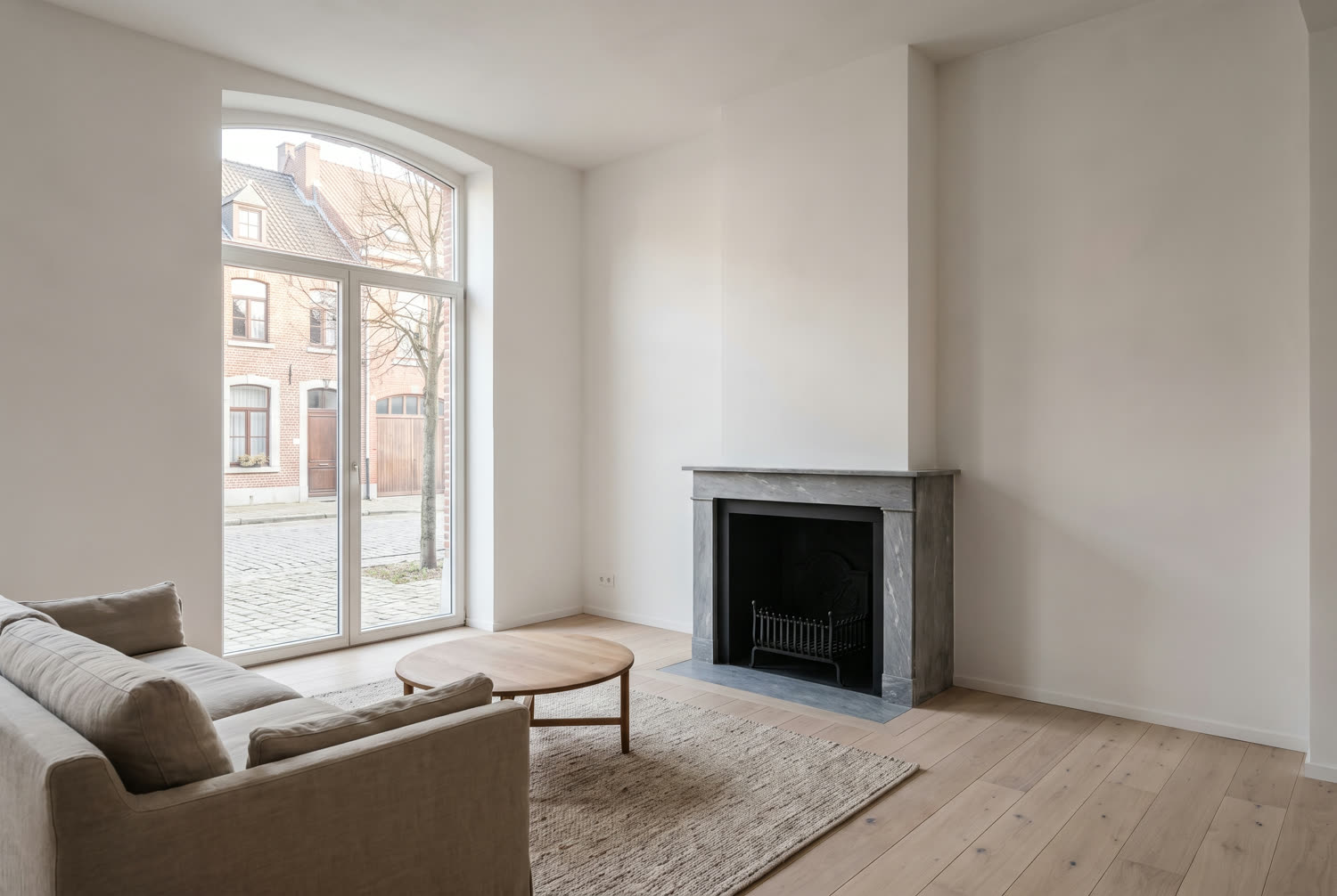 Séjour rénové d'une maison de Wavre, plancher restauré, enduit lisse et cheminée en marbre conservée